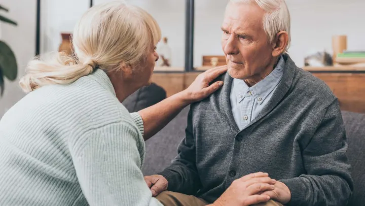 elderly woman consoling elderly man